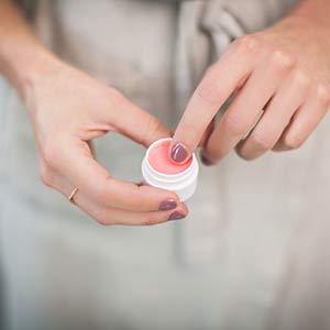 Photo of hands holding and poking a lip balm. Click on the photo for more information about DIY lip balm.  